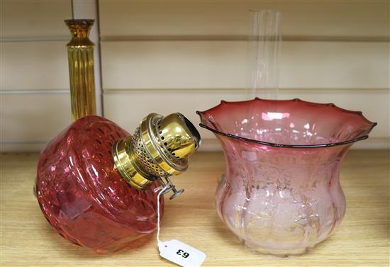 A cranberry glass oil lamp and shade on brass column